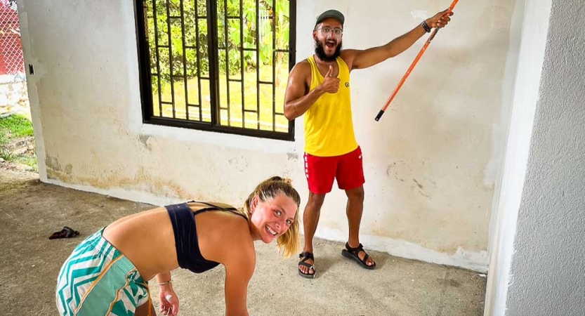 Two people smile while they pause a painting project for the photo. 